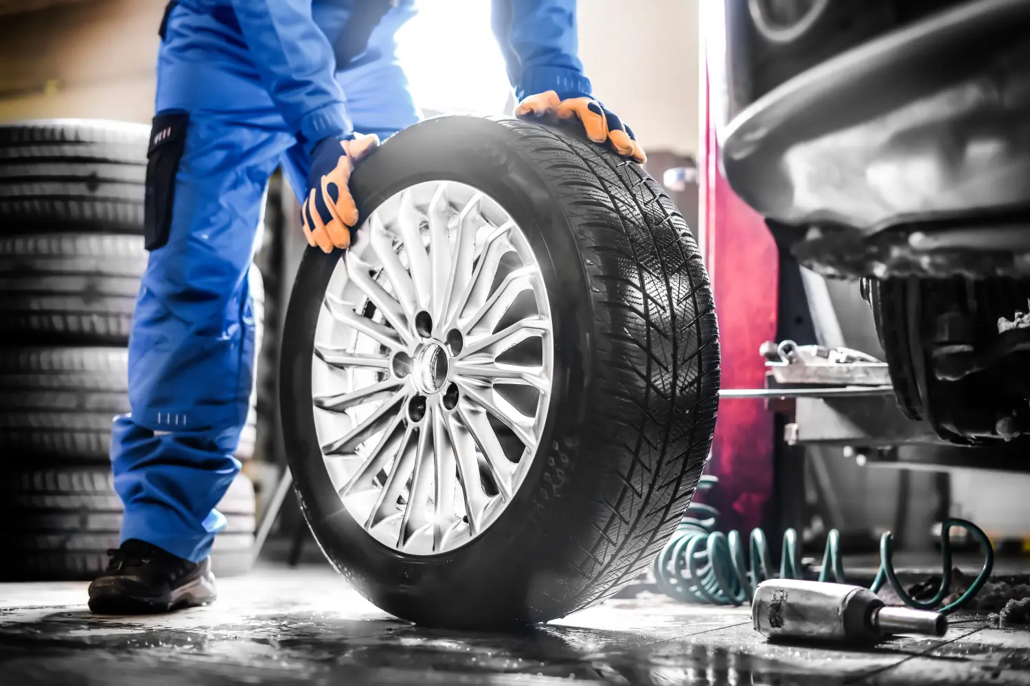 Reifenservice, Aufbereitung, A.P Detailing, Außenaufbereitung, Innenaufbereitung, Zusatzleistungen, Reifen Einlagerung, Reifenmontage, Reifenprüfung & Beratung, Reifenwechsel, Reifen wuchten, Automechaniker, der in einer Werkstatt arbeitet und einen Leichtmetallfelgenreifen wechselt.